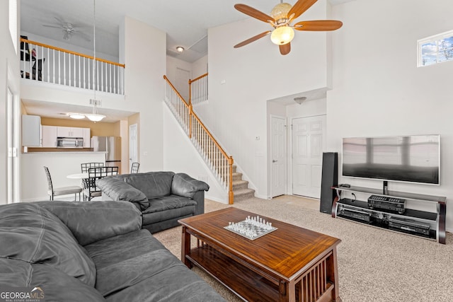 living room featuring ceiling fan, carpet floors, and a high ceiling