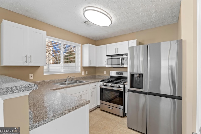 kitchen with white cabinetry, stainless steel appliances, sink, and a textured ceiling