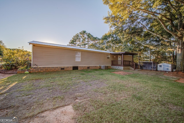 back of house featuring a storage shed, central AC, and a lawn