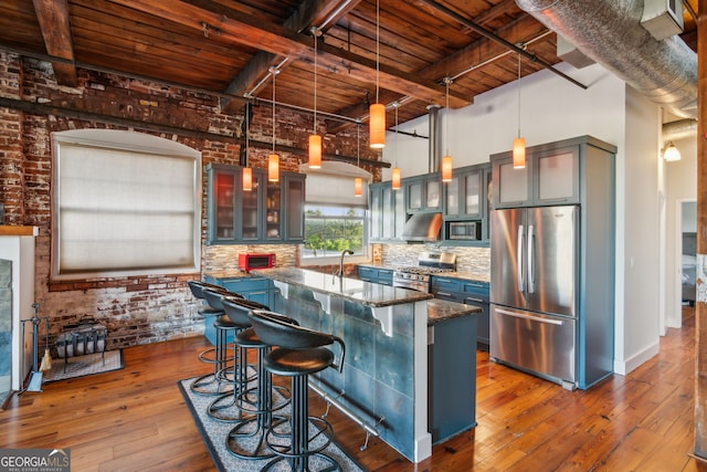 kitchen featuring tasteful backsplash, hardwood / wood-style flooring, wood ceiling, brick wall, and appliances with stainless steel finishes