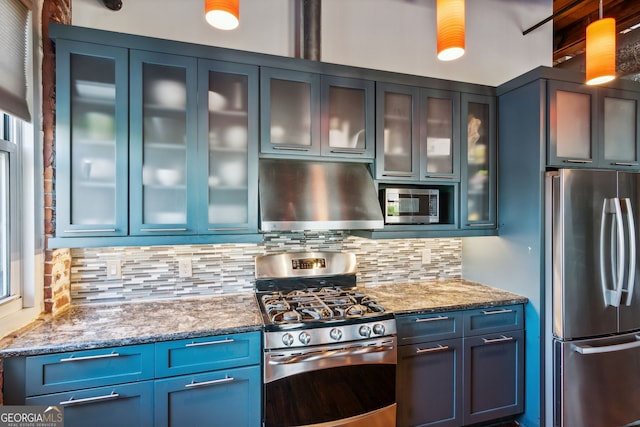 kitchen with light stone counters, appliances with stainless steel finishes, blue cabinets, ventilation hood, and backsplash