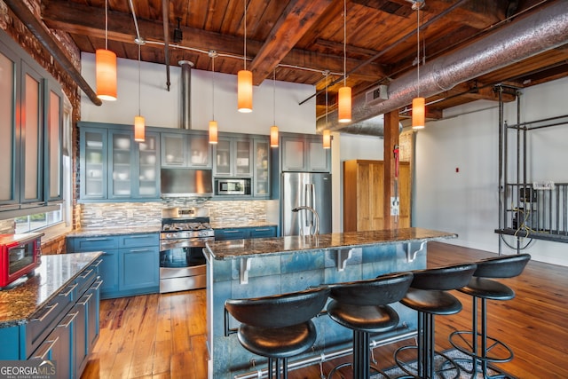 kitchen featuring stainless steel appliances, light wood finished floors, a kitchen bar, and tasteful backsplash