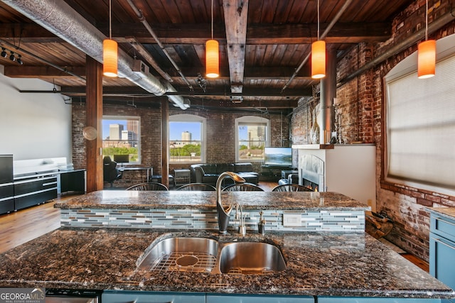 kitchen with wood ceiling, brick wall, open floor plan, dark stone countertops, and wood finished floors