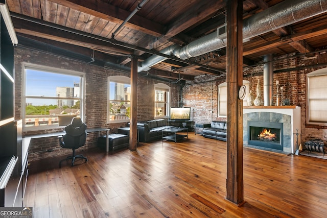 unfurnished living room with beam ceiling, a tiled fireplace, brick wall, wooden ceiling, and hardwood / wood-style floors