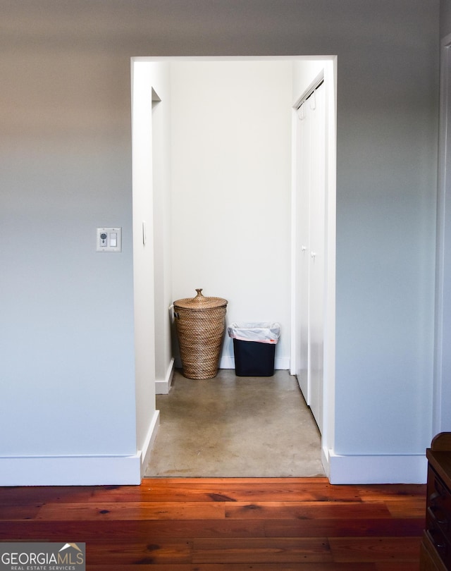 hall featuring concrete flooring and baseboards