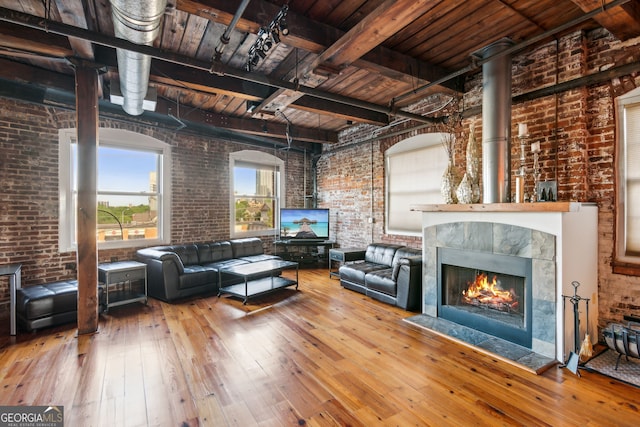 unfurnished living room with a tile fireplace, wooden ceiling, hardwood / wood-style flooring, brick wall, and beamed ceiling