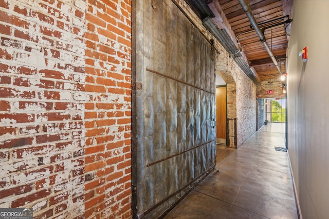 hallway featuring brick wall, concrete floors, and visible vents