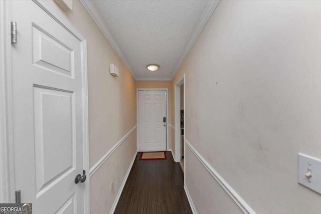 corridor featuring crown molding, dark wood-type flooring, and a textured ceiling