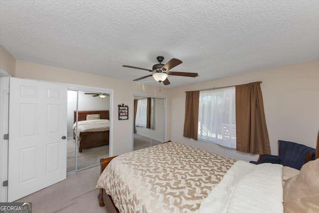 bedroom with two closets, a textured ceiling, and ceiling fan