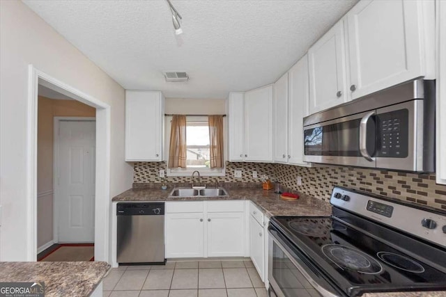 kitchen with light tile patterned flooring, sink, white cabinetry, appliances with stainless steel finishes, and decorative backsplash