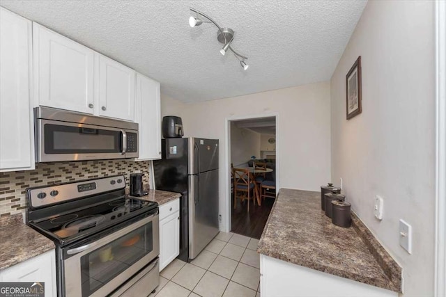 kitchen featuring stainless steel appliances, light tile patterned floors, decorative backsplash, and white cabinets