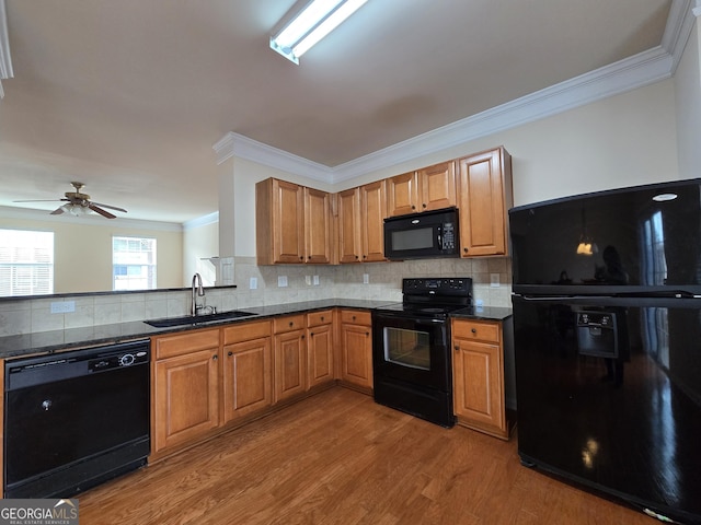 kitchen featuring sink, backsplash, light wood-type flooring, and black appliances