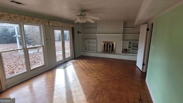 unfurnished living room with ceiling fan, a textured ceiling, a brick fireplace, parquet flooring, and french doors