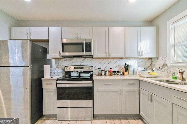 kitchen featuring tasteful backsplash, white cabinetry, appliances with stainless steel finishes, and sink