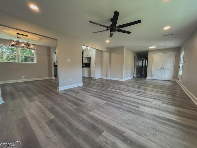 unfurnished living room with wood-type flooring and ceiling fan with notable chandelier