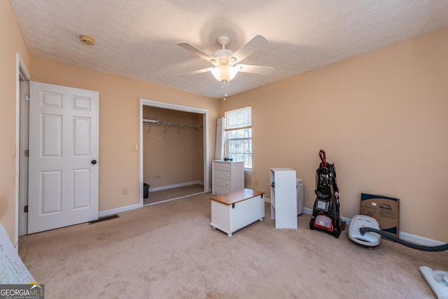 unfurnished bedroom with ceiling fan, light colored carpet, a textured ceiling, and a closet