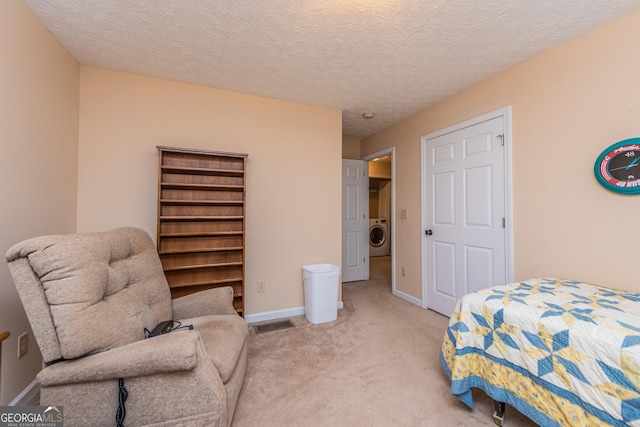 carpeted bedroom with washer / dryer and a textured ceiling