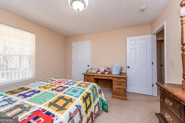 bedroom with light carpet and a textured ceiling