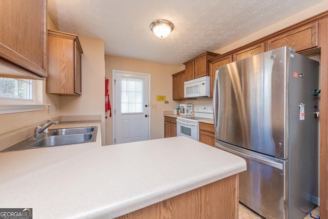 kitchen with white appliances, a healthy amount of sunlight, kitchen peninsula, and sink