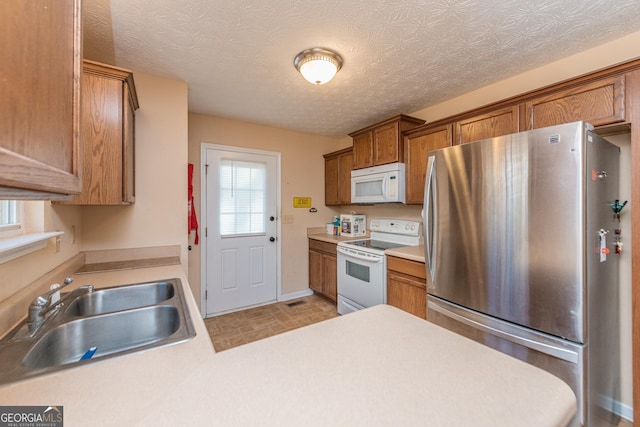 kitchen with sink, a textured ceiling, and white appliances