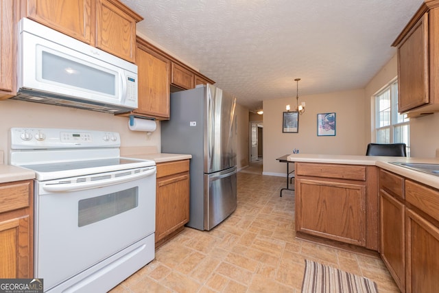 kitchen featuring white appliances, a chandelier, hanging light fixtures, and a textured ceiling