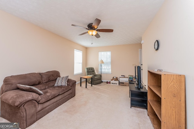 carpeted living room featuring ceiling fan and a textured ceiling