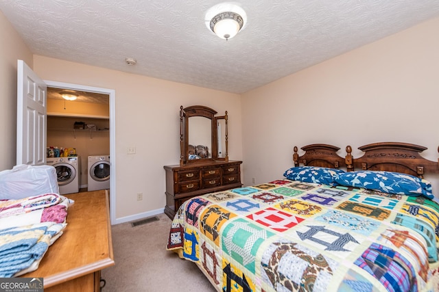 bedroom with light carpet, a textured ceiling, and washing machine and clothes dryer