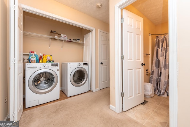 clothes washing area with separate washer and dryer, light colored carpet, and a textured ceiling