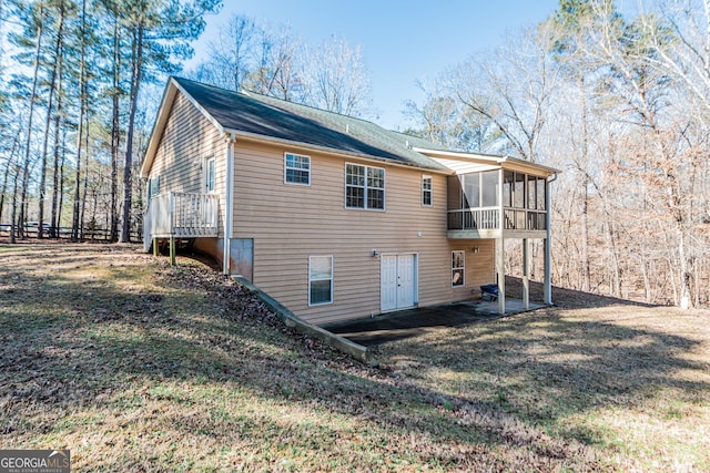 back of house featuring a sunroom and a lawn