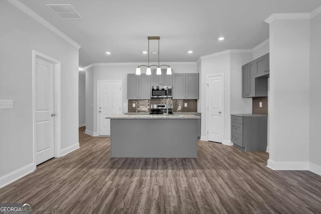 kitchen with tasteful backsplash, hanging light fixtures, a center island with sink, gray cabinets, and stainless steel appliances