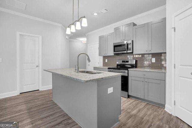 kitchen with pendant lighting, sink, gray cabinetry, a kitchen island with sink, and stainless steel appliances