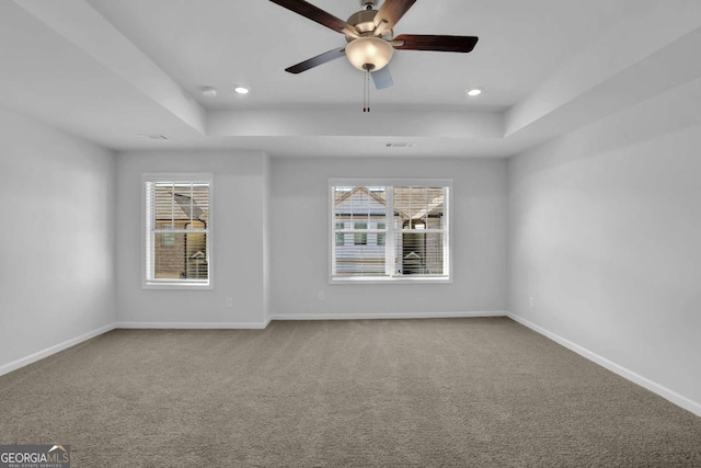 spare room with carpet floors, ceiling fan, and a tray ceiling