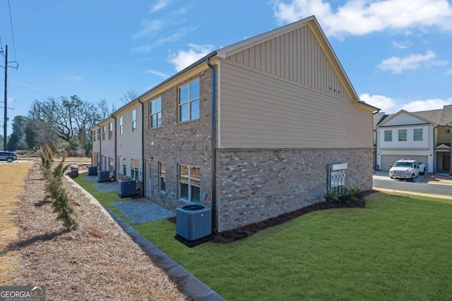 view of property exterior with a garage, a lawn, and central air condition unit