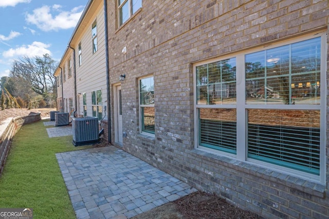 view of side of home featuring central air condition unit, a patio, and a lawn