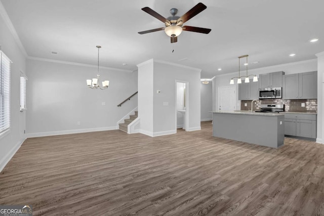 unfurnished living room with ornamental molding, ceiling fan with notable chandelier, sink, and hardwood / wood-style floors