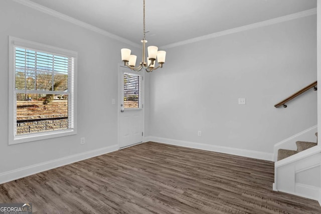 unfurnished dining area featuring dark wood-type flooring, ornamental molding, and a notable chandelier