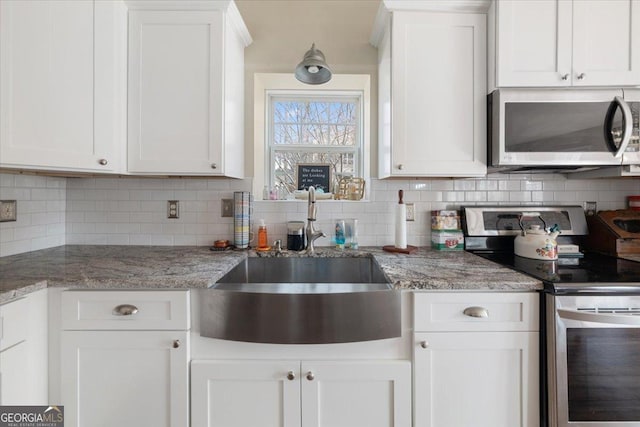 kitchen featuring stainless steel appliances, light stone countertops, decorative backsplash, and white cabinets