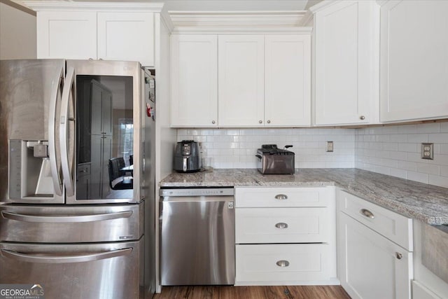 kitchen featuring white cabinetry, tasteful backsplash, light stone countertops, and appliances with stainless steel finishes