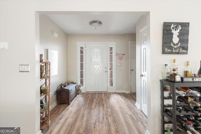 entryway with a textured ceiling and light wood-type flooring