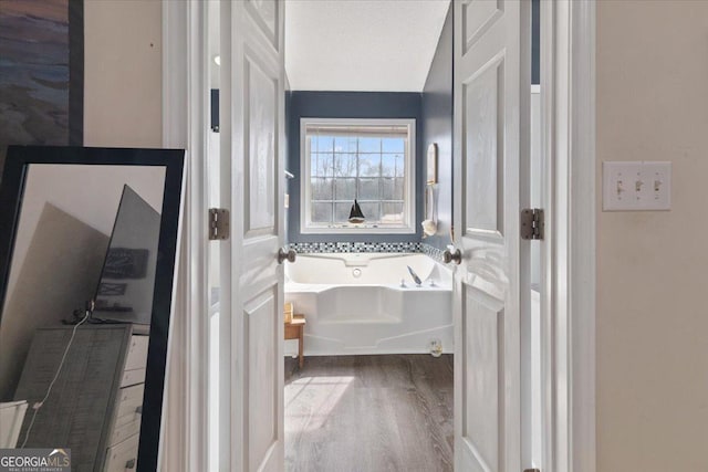 bathroom featuring hardwood / wood-style floors, a textured ceiling, and a washtub