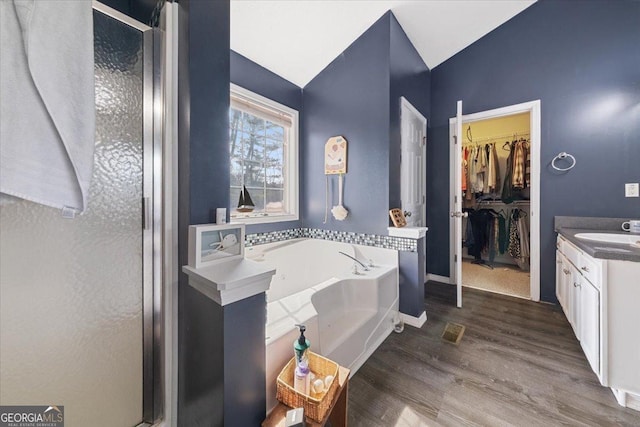 bathroom featuring hardwood / wood-style flooring, plus walk in shower, and vanity