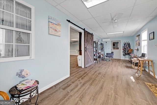 interior space with a barn door, hardwood / wood-style floors, and a drop ceiling