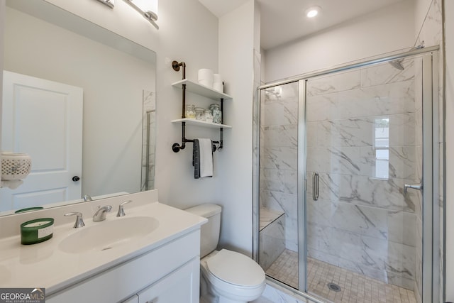 bathroom featuring vanity, a shower with shower door, and toilet