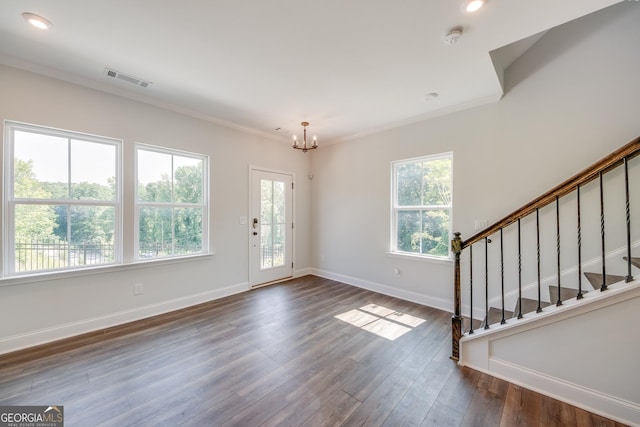 foyer with an inviting chandelier, ornamental molding, and dark hardwood / wood-style flooring