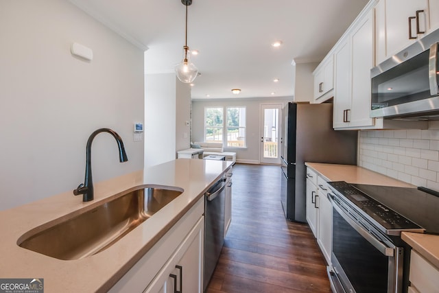 kitchen with sink, hanging light fixtures, appliances with stainless steel finishes, white cabinets, and backsplash