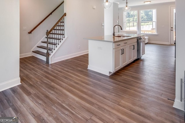 kitchen with sink, white cabinetry, stainless steel dishwasher, pendant lighting, and a kitchen island with sink