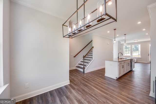 kitchen with sink, dark wood-type flooring, white cabinets, a center island with sink, and decorative light fixtures