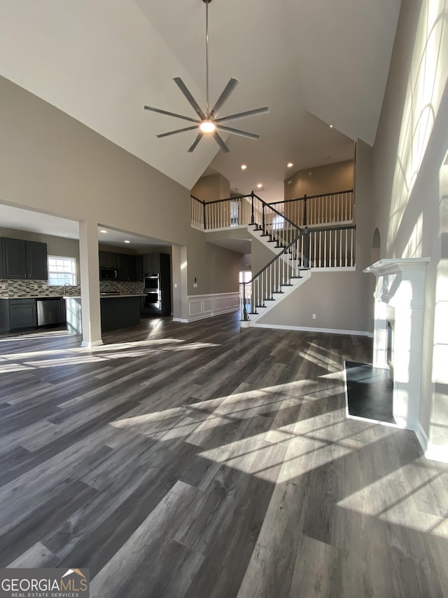 unfurnished living room featuring ceiling fan, a towering ceiling, and dark hardwood / wood-style flooring