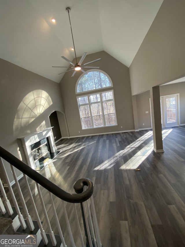 unfurnished living room featuring ceiling fan, dark wood-type flooring, and high vaulted ceiling