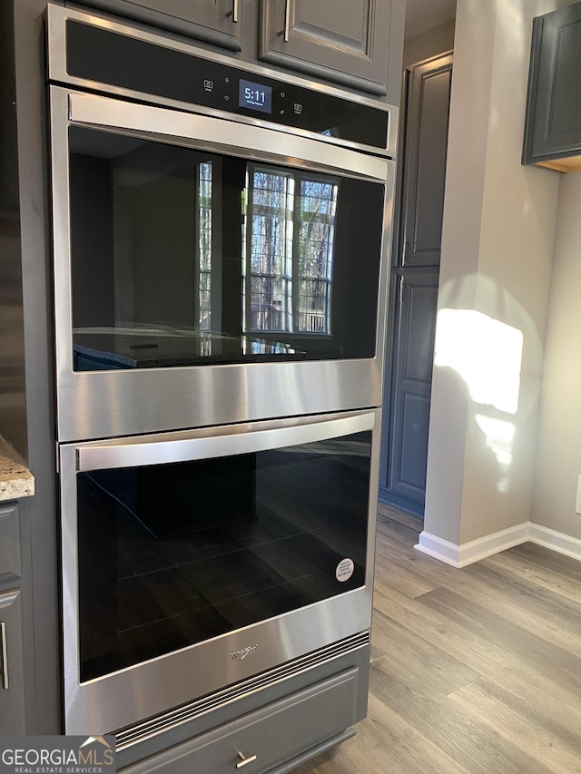 details featuring light stone counters, light hardwood / wood-style flooring, and stainless steel double oven